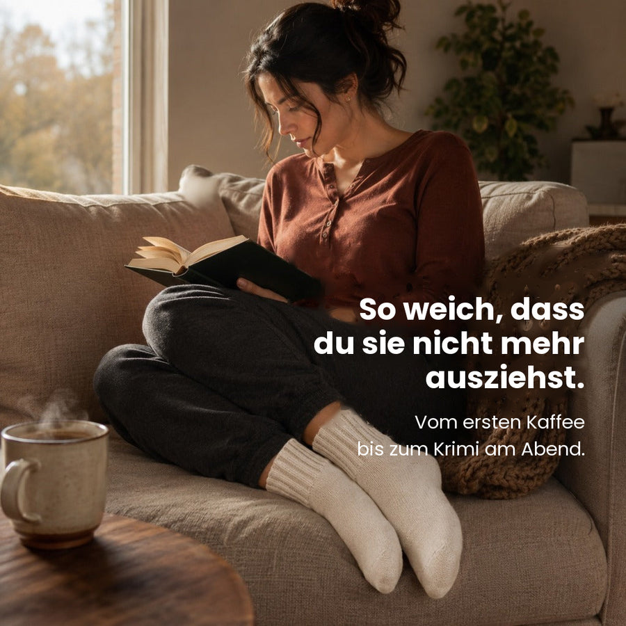 Füße in espressofarbenen Kuschelsocken auf dem Sofa
