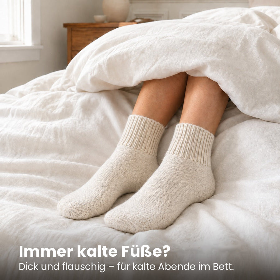 Füße in Kuschelsocken unter der Bettdecke