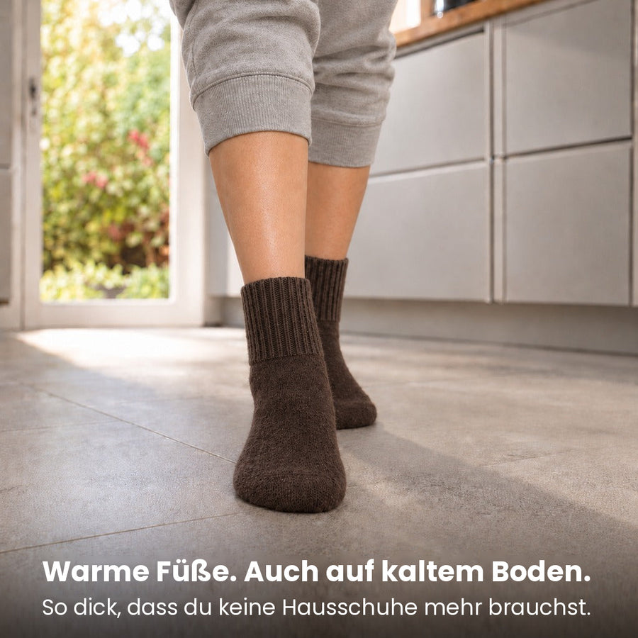 Füße in espressofarbenen Socken auf kaltem Boden